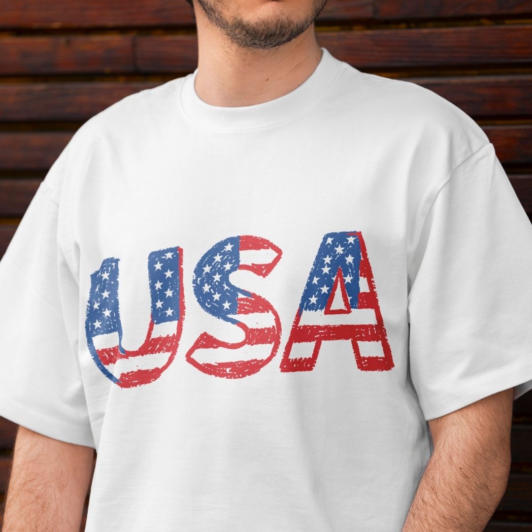 Person wearing a white t-shirt with 'USA' printed in American flag colors against a wooden background