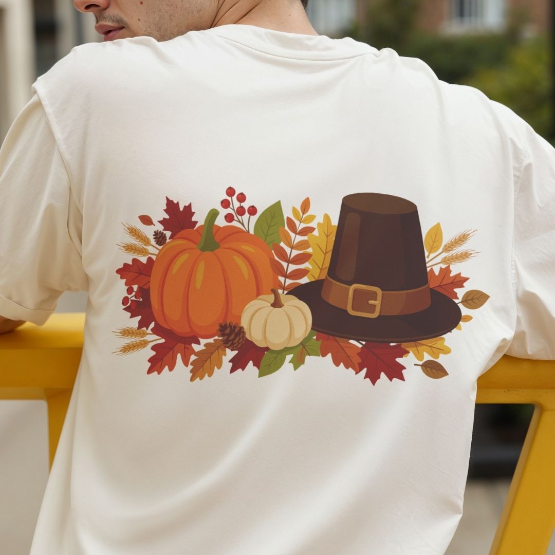 Person wearing a white t-shirt with a Thanksgiving design featuring pumpkins and a pilgrim hat.