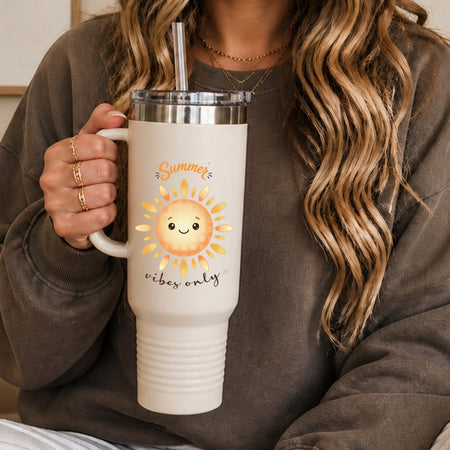 A person holding a cream-colored stainless steel tumbler with a lid and straw, decorated with a happy cartoon sun graphic and the text "Summer vibes only".