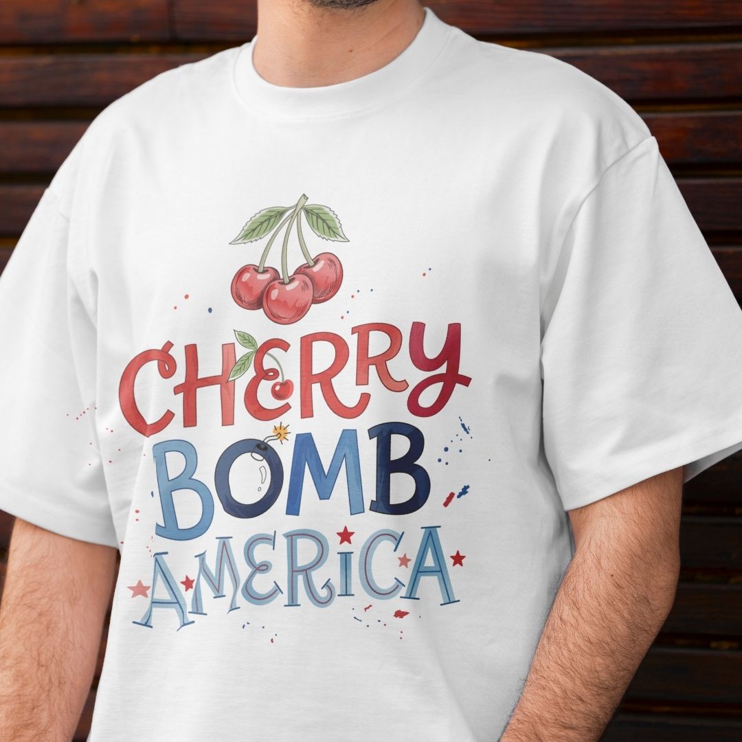 White t-shirt with 'Cherry Bomb America' graphic design on a wooden background