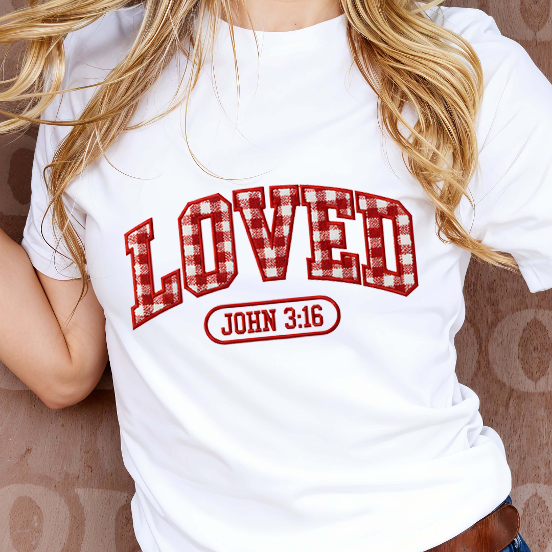 White t-shirt with red plaid 'LOVED' text and 'JOHN 3:16' on a patterned background