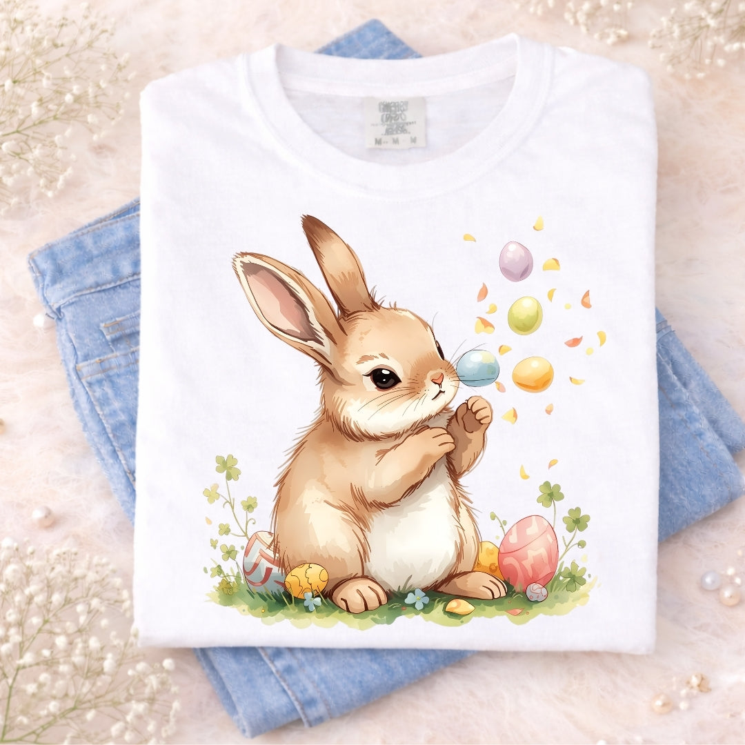 White t-shirt with a cartoon bunny and Easter eggs design on a light background