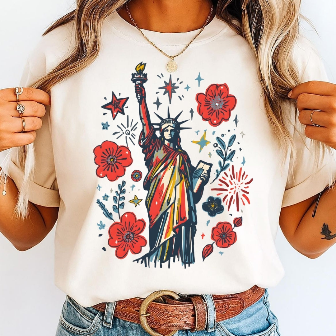 Person wearing a white t-shirt with a colorful graphic of the Statue of Liberty and flowers.