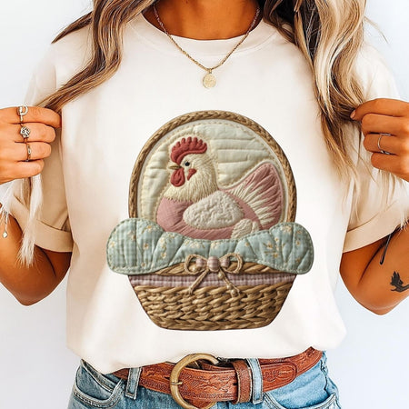 Person wearing a white t-shirt with a rooster design in a basket on a plain background
