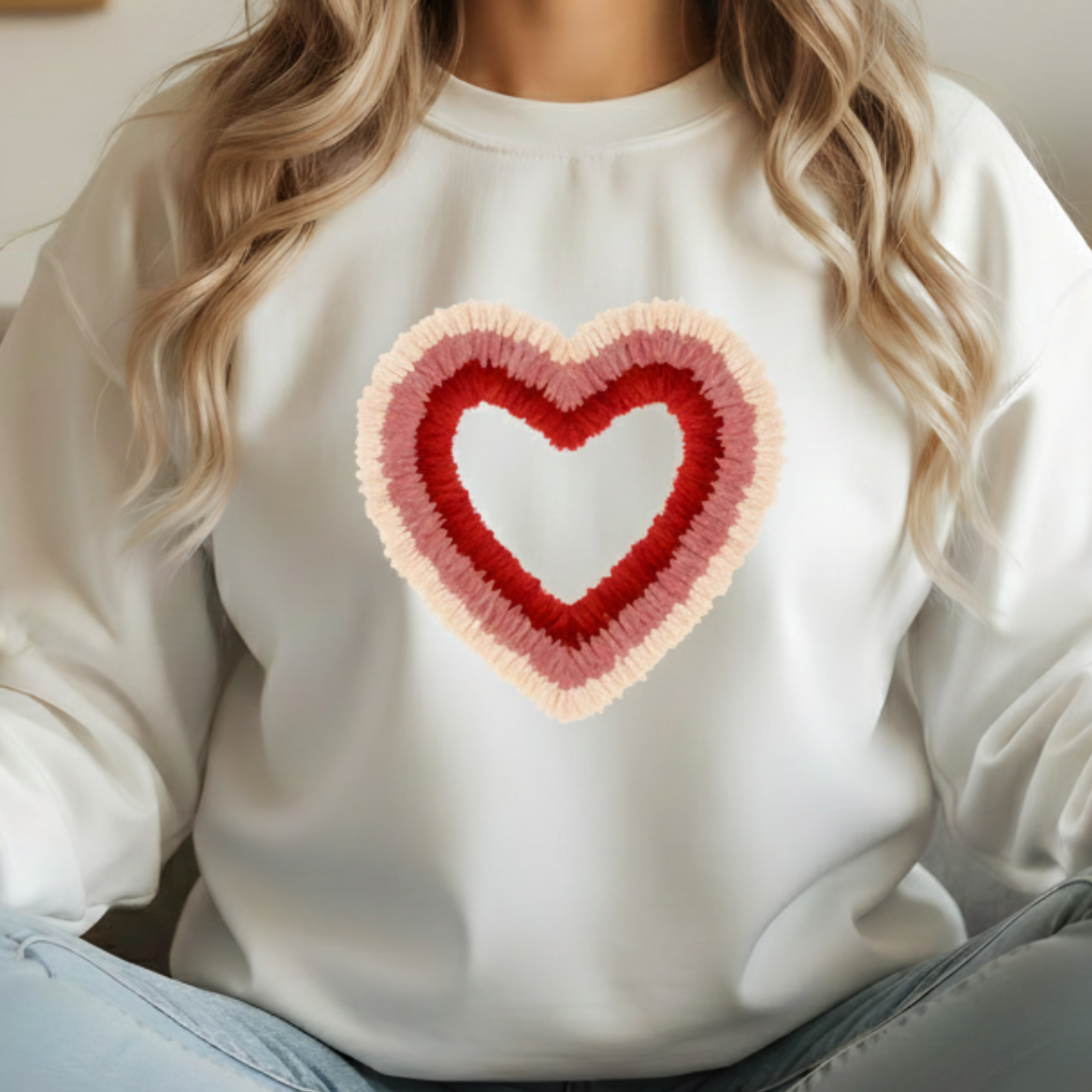 White sweatshirt with a heart-shaped design worn by a person with blonde hair.