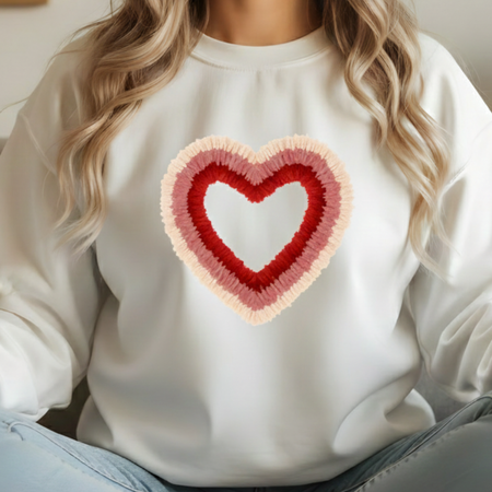 White sweatshirt with a heart-shaped design worn by a person with blonde hair.