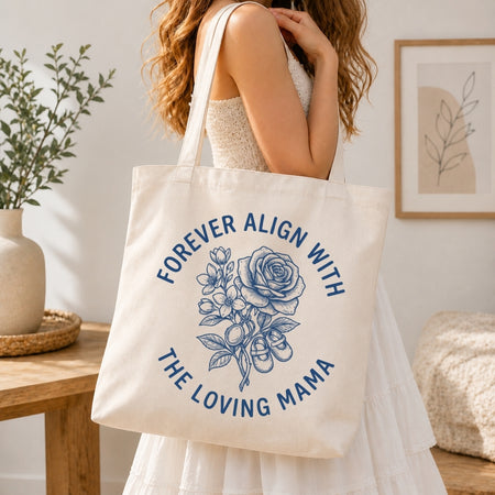 Woman in a white tiered dress carrying a cream-colored canvas tote bag printed with a large blue retro rose bouquet graphic over her shoulder.