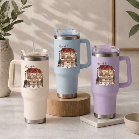 Three insulated tumblers in beige, light blue, and purple, each featuring the quaint French cafe and boulangerie design.