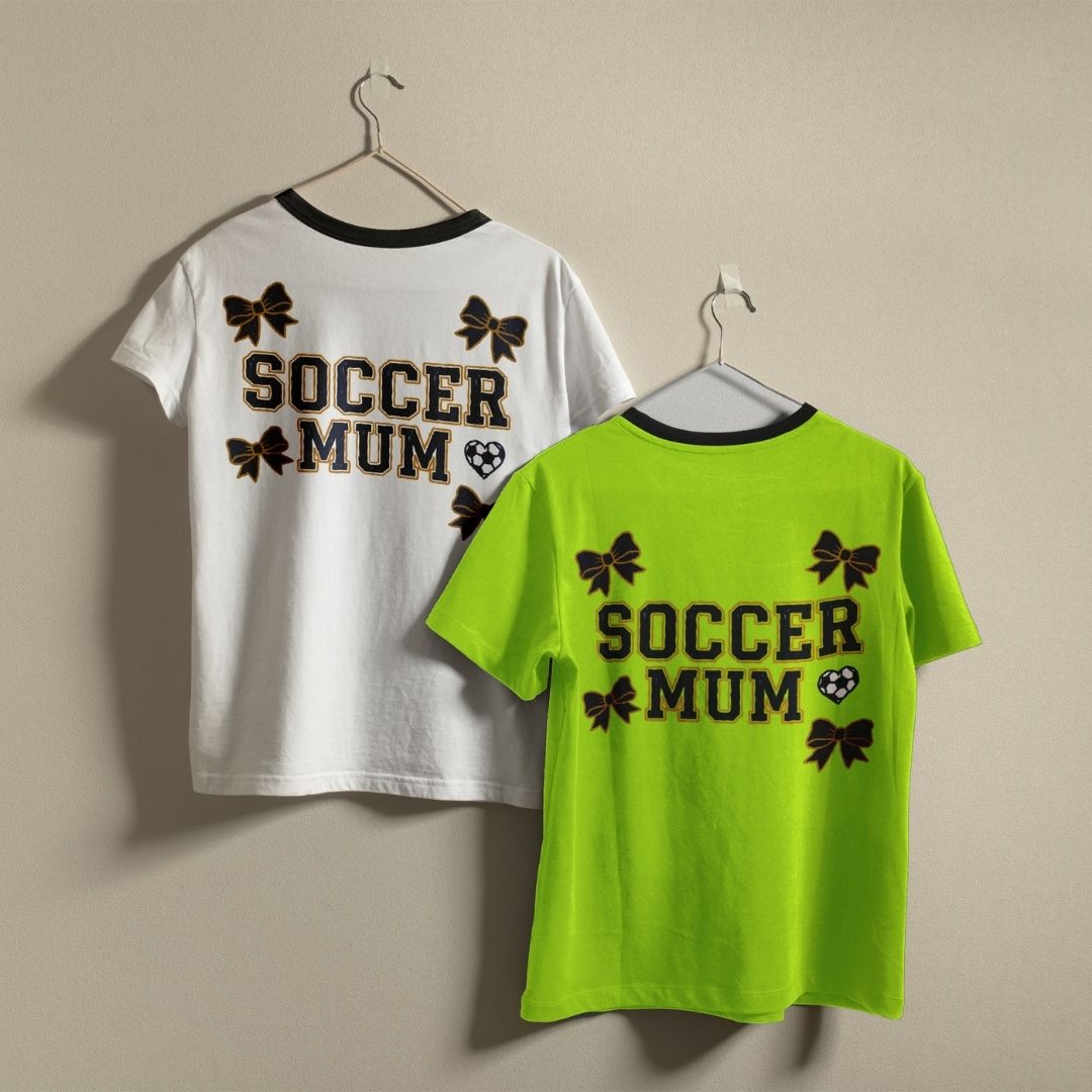 Two t-shirts with 'Soccer Mum' text on hangers against a beige background