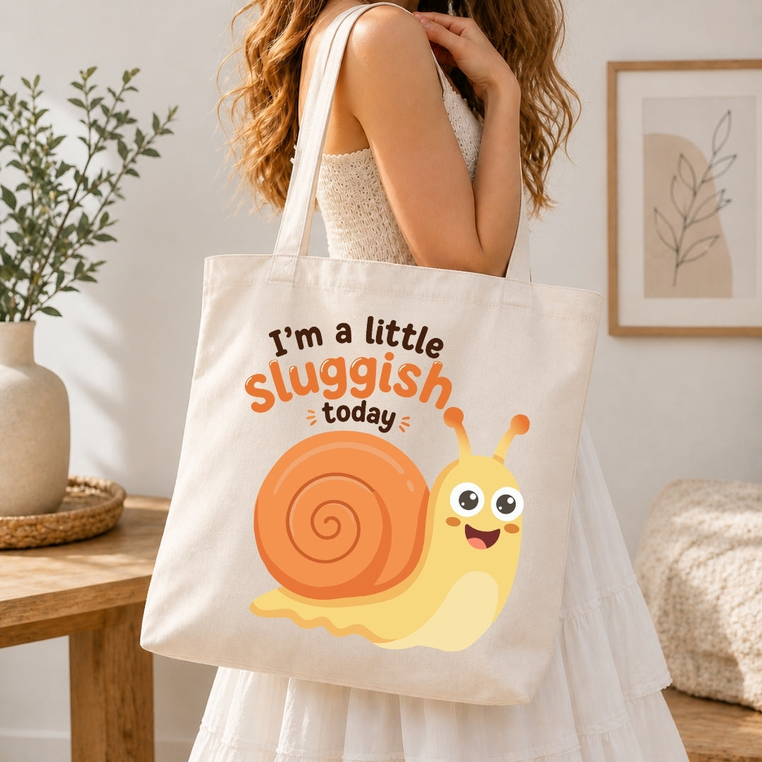 A person holding a cream-colored tote bag printed with the cute, smiling cartoon snail graphic and the text "I’m a little sluggish today."