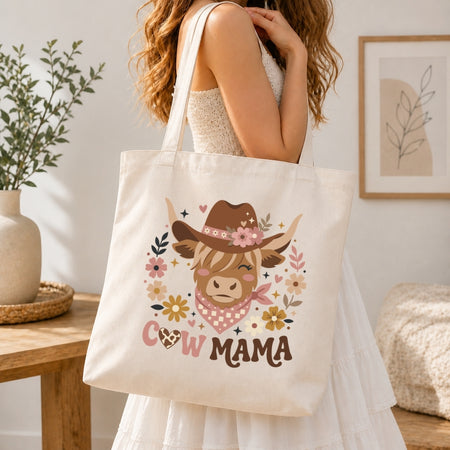 Person holding a tote bag with a cow illustration and 'Cow Mama' text in a home setting.
