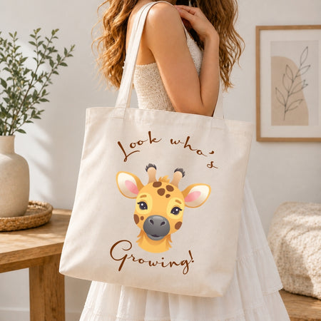 Woman carrying a cream-colored canvas tote bag over her shoulder featuring the cute giraffe illustration and Look Whos Growing text.