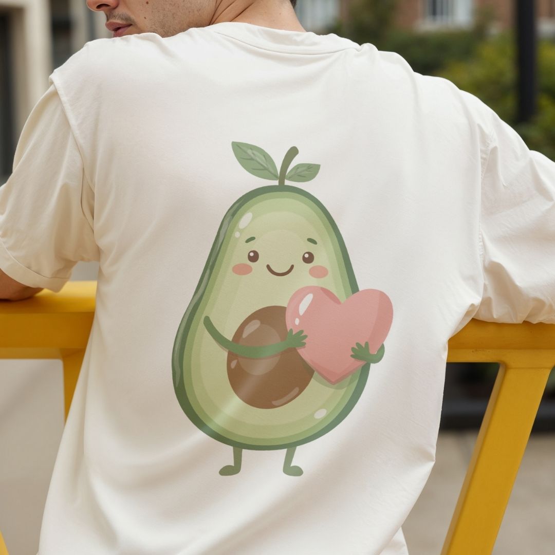 Person wearing a white t-shirt with a cartoon avocado holding a heart design.