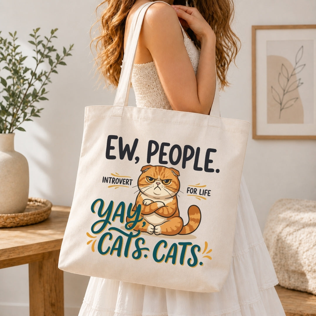 Woman in a white tiered dress carrying a cream canvas tote bag printed with a large funny grumpy cat "Ew, People. Yay, Cats." illustration over her shoulder.