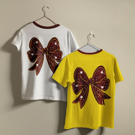 Two t-shirts with a large brown bow design on a beige background