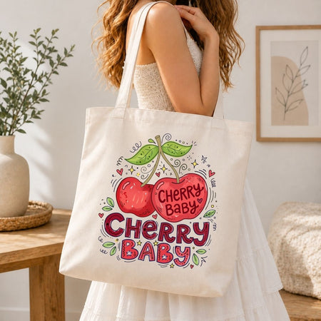 Person holding a tote bag with 'Cherry Baby' design in a home setting