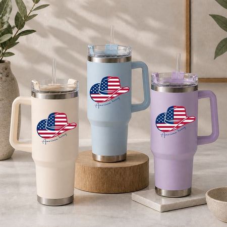 Three insulated travel tumblers in cream, light blue, and lavender purple arranged on a table, all showcasing the patriotic western design.