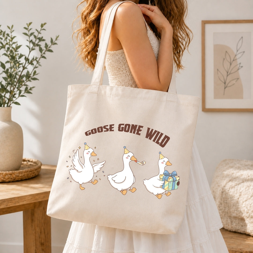 Person in a white dress carrying a canvas tote bag printed with the humorous "GOOSE GONE WILD" geese graphic.