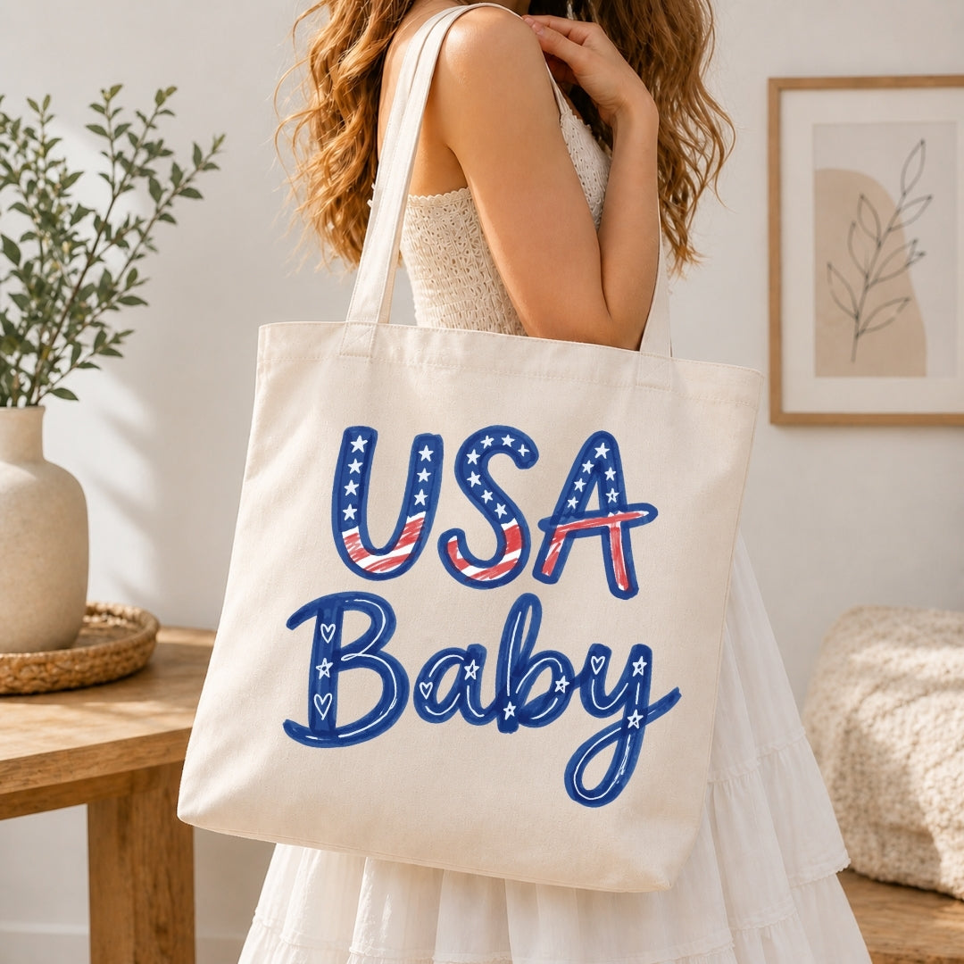 Person holding a tote bag with 'USA Baby' text in a home setting