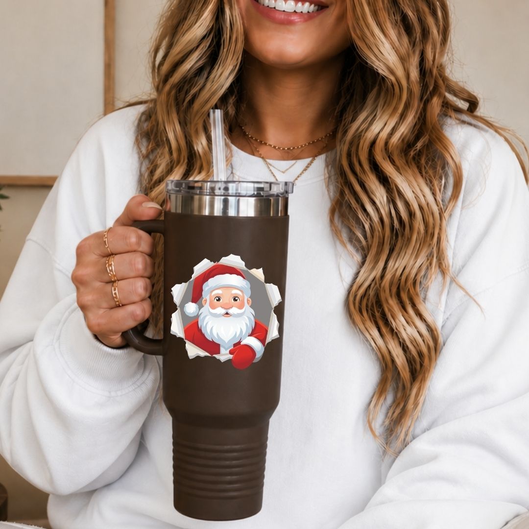 Woman holding a brown travel tumbler with a straw, featuring a cheerful Santa Claus breaking through a torn paper background.