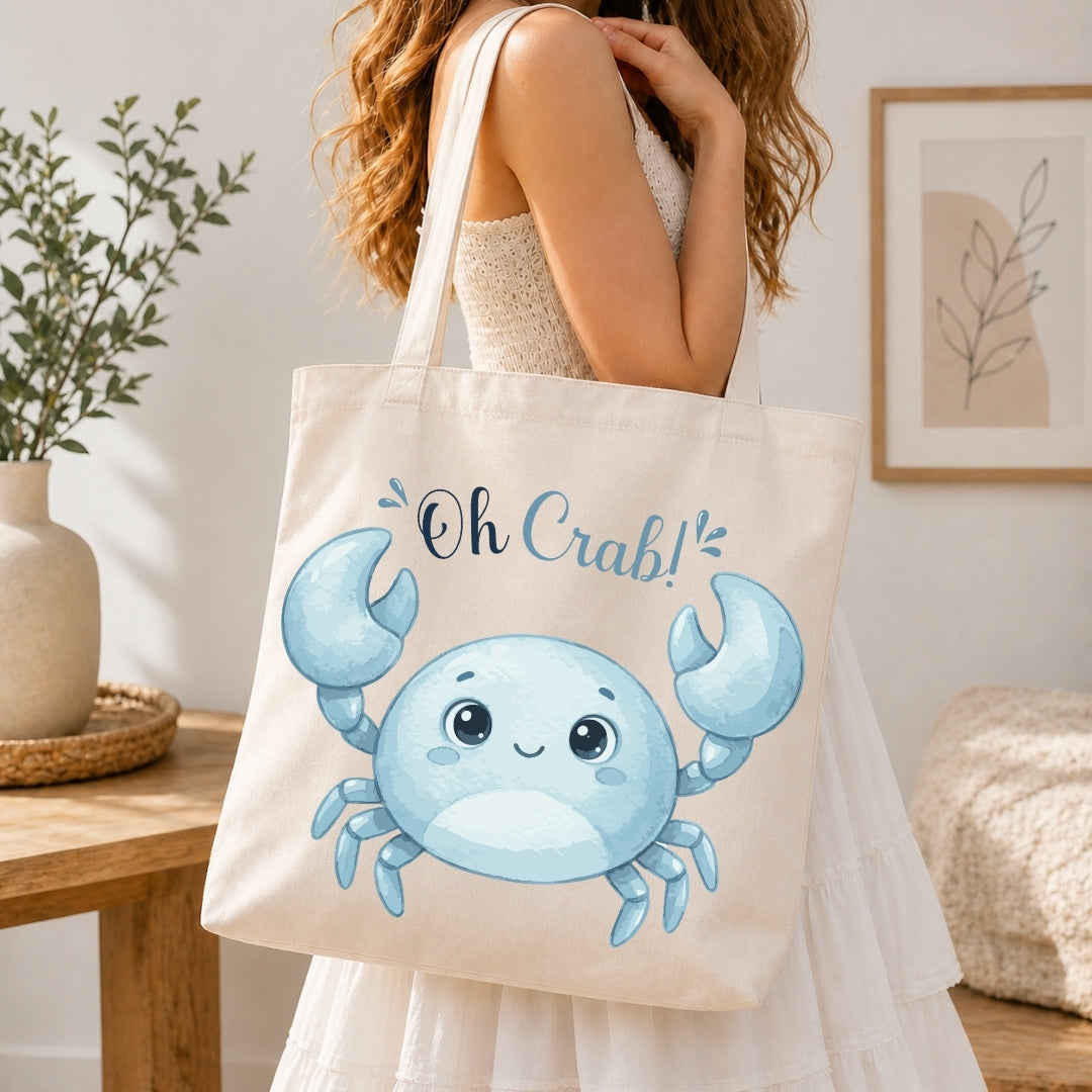 A woman holding a cream-colored tote bag printed with a blue cartoon crab graphic and the text "Oh Crab!"