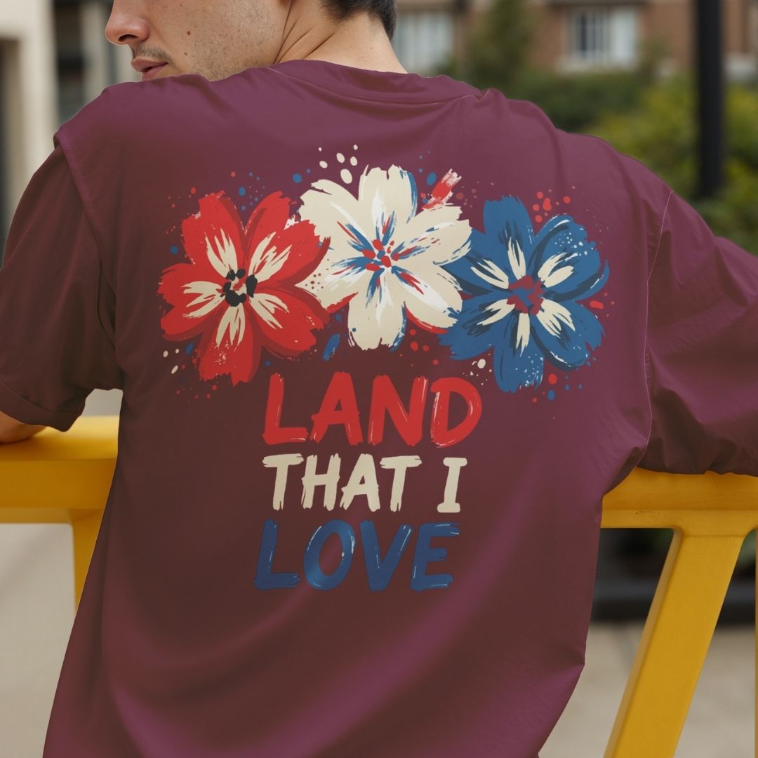Person wearing a maroon t-shirt with floral designs and 'LAND THAT I LOVE' text.