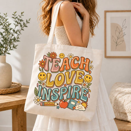Person in a white dress carrying a canvas tote bag printed with the vibrant "TEACH LOVE INSPIRE" school and floral graphic.