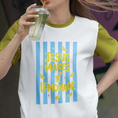Person wearing a t-shirt with 'Jesus Makes Lemonade' design, holding a drink.
