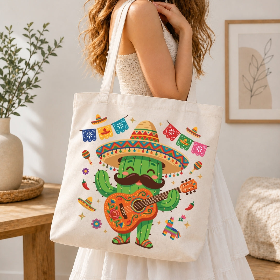 A woman in a white dress carries a cream canvas tote bag decorated with a colorful cartoon cactus wearing a sombrero and playing a guitar, set against a warm, softly lit indoor background.