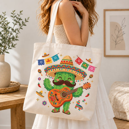 A woman in a white dress carries a cream canvas tote bag decorated with a colorful cartoon cactus wearing a sombrero and playing a guitar, set against a warm, softly lit indoor background.