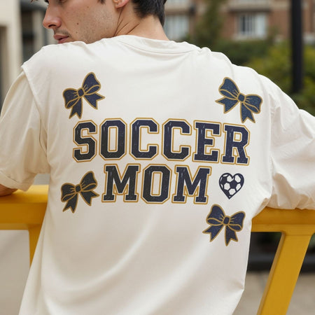 Person wearing a white t-shirt with 'Soccer Mom' text and decorative elements.