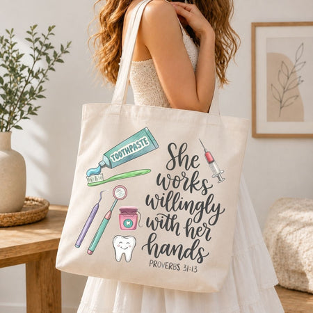 A woman wearing a white dress carries a cream canvas tote bag with a tooth-themed graphic and the quote 'She works willingly with her hands' from Proverbs 3:13. The tote bag features illustrations of a toothpaste tube, toothbrush, syringe, dental tools, a tooth, and a smiling tooth.