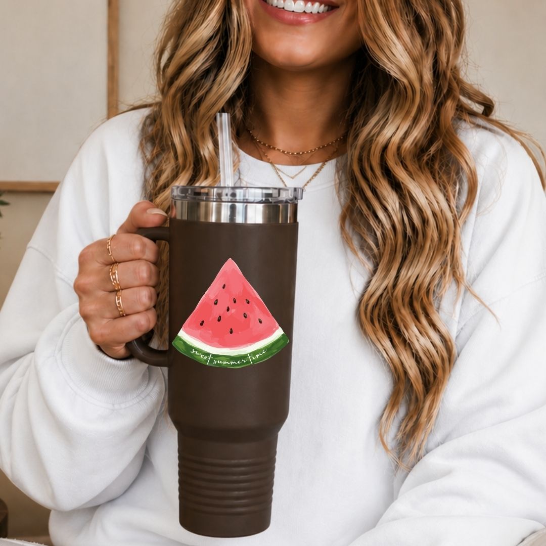 A woman holding a large brown insulated travel tumbler with a handle and straw, decorated with the "sweet summer time" watermelon slice design.