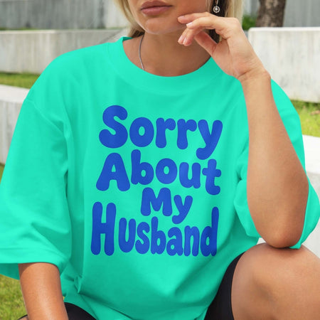 Person wearing a teal t-shirt with 'Sorry About My Husband' text in blue.