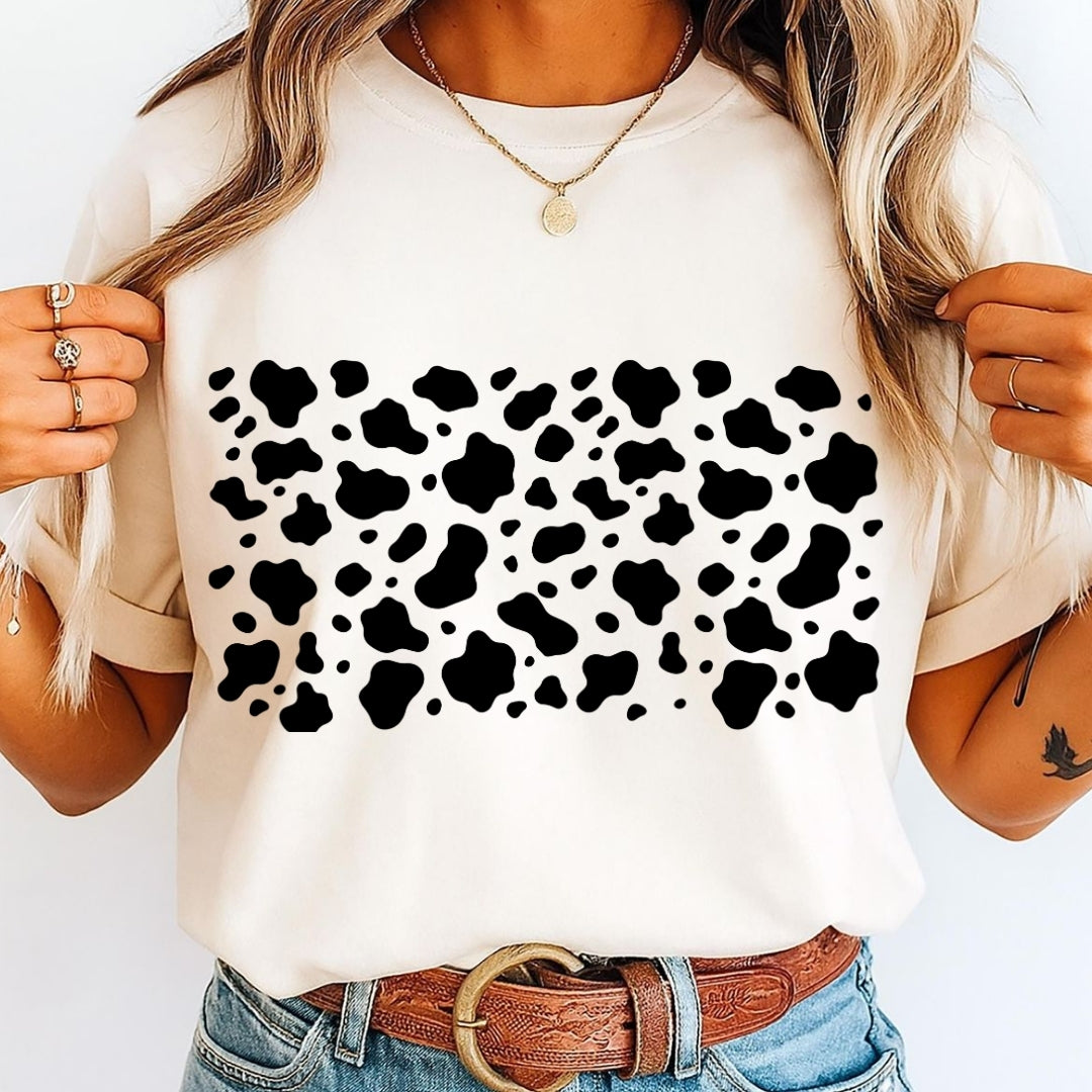 White t-shirt with black cow print worn by a person on a white background