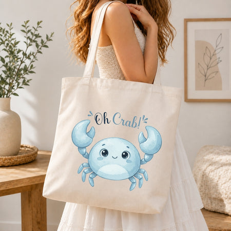 Person holding a tote bag with a blue crab design and 'Oh Crab!' text.