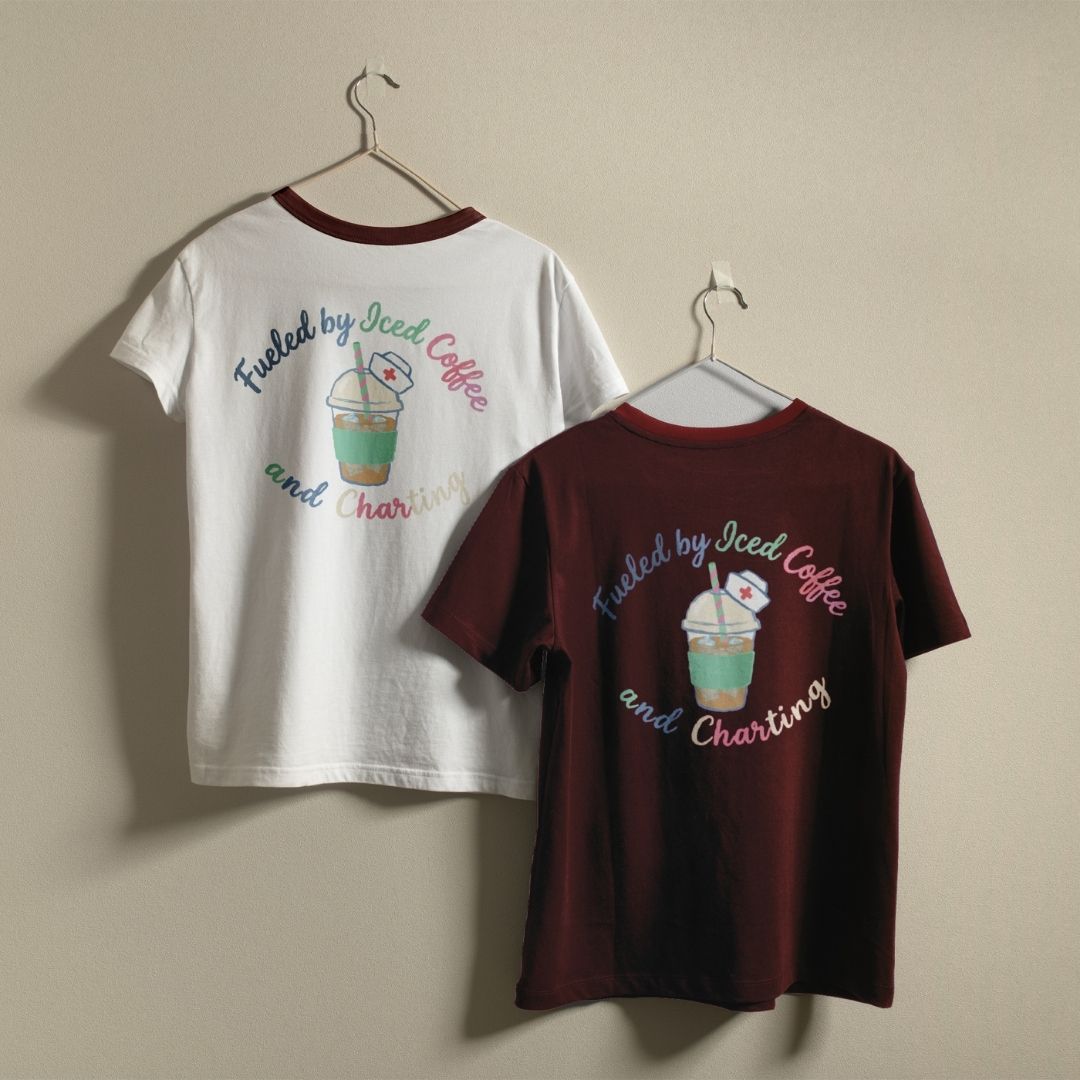 Two t-shirts, one white and one maroon, with a graphic design and text on hangers against a beige wall.