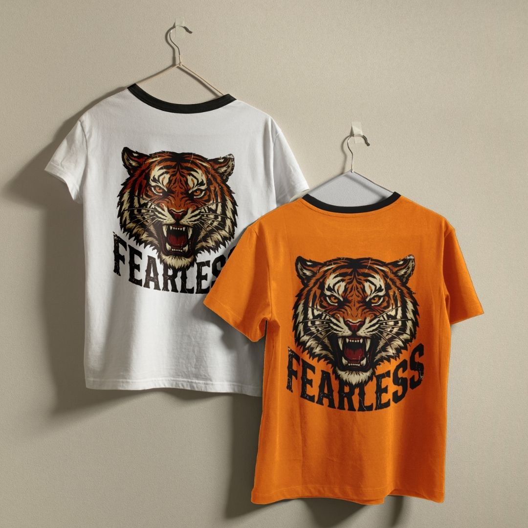 Two t-shirts with a tiger graphic and 'FEARLESS' text on hangers against a beige background.