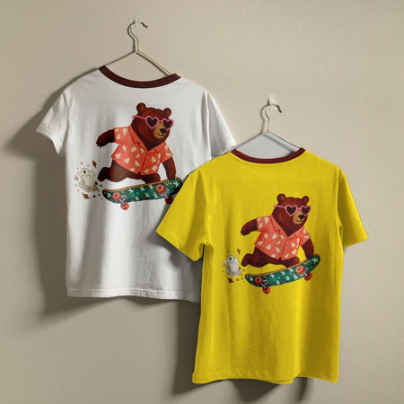 Two t-shirts, one white and one yellow, with a bear graphic on hangers against a beige background.