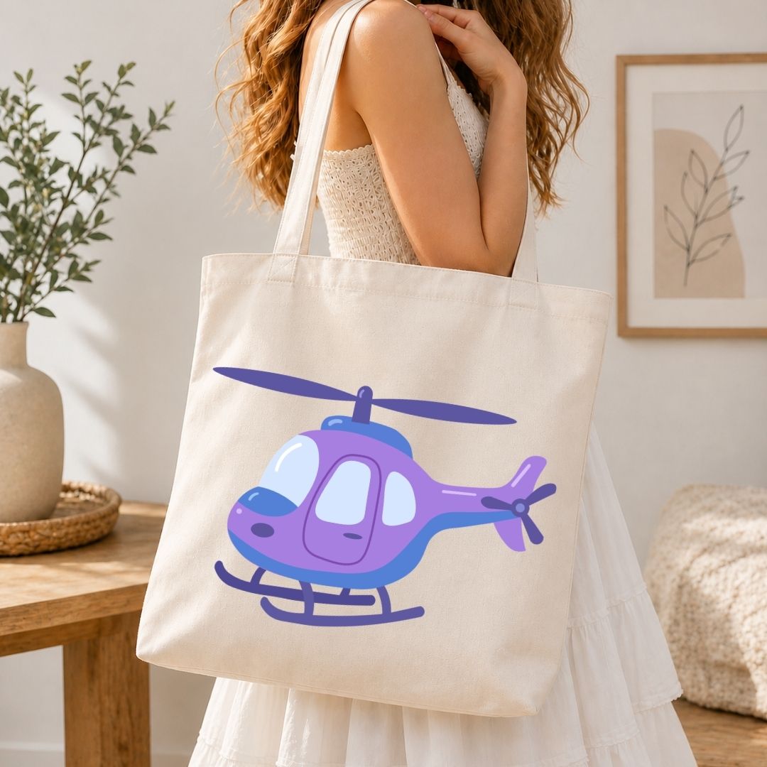 A woman wearing a white dress carries a cream canvas tote bag featuring a purple and blue cartoon helicopter illustration, set in a bright, modern room.
