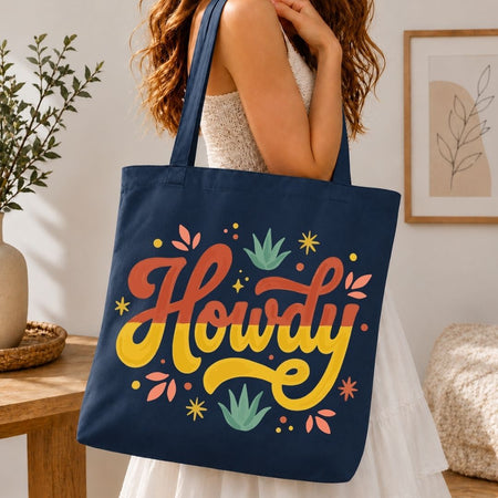 A woman carrying a dark navy blue canvas tote bag over her shoulder printed with a large, vibrant yellow and red "Howdy" logo.