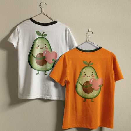 Two t-shirts, one white and one orange, with a cartoon avocado design holding a heart on a beige background.