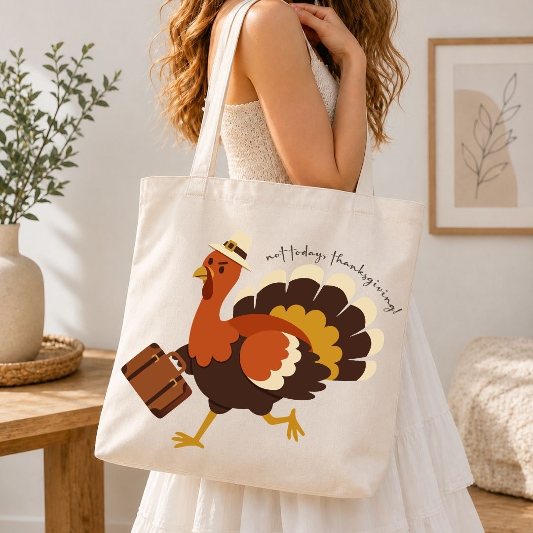 A woman wearing a white dress carries a cream canvas tote bag with a colorful cartoon turkey graphic and the text 'meet today, thanksgiving!' in a bright indoor room.