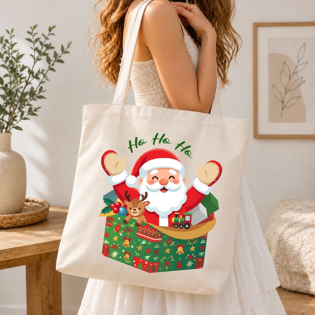 A woman wearing a white dress carries a cream canvas tote bag with a colorful Christmas Santa graphic and the text 'Ho Ho Ho' in a bright indoor room.