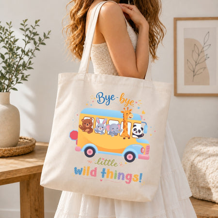 Person holding a tote bag with a colorful design of animals on a bus and text.