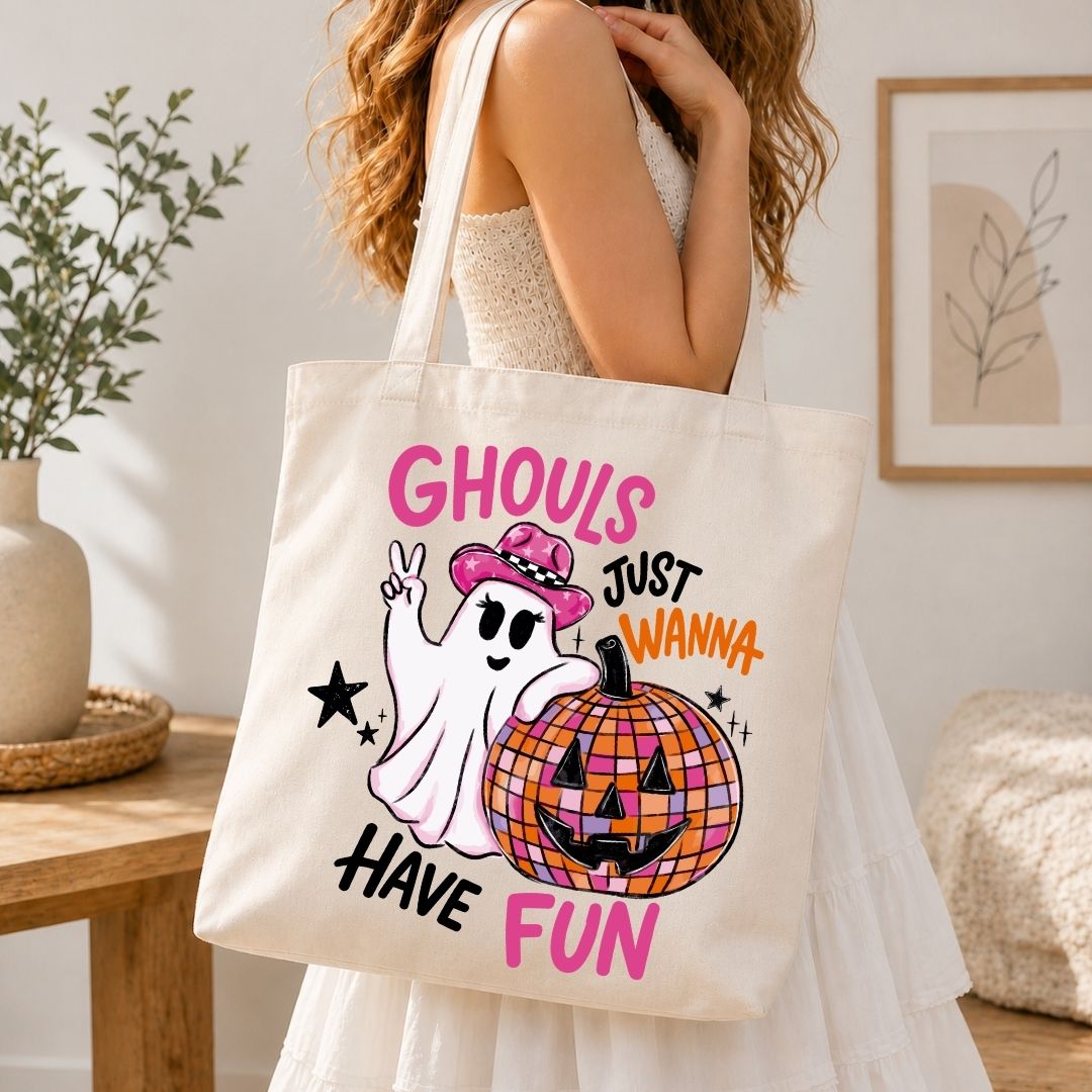 A person wearing a white dress and carrying a natural canvas tote bag printed with the Ghouls Just Wanna Have Fun Halloween graphic.