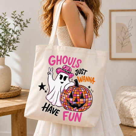 A person wearing a white dress and carrying a natural canvas tote bag printed with the Ghouls Just Wanna Have Fun Halloween graphic.