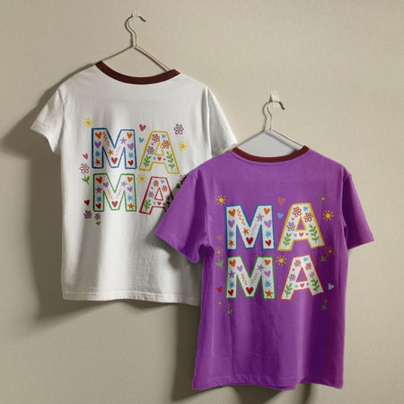 White and purple t-shirts with 'MAMA' text on hangers against a beige wall.