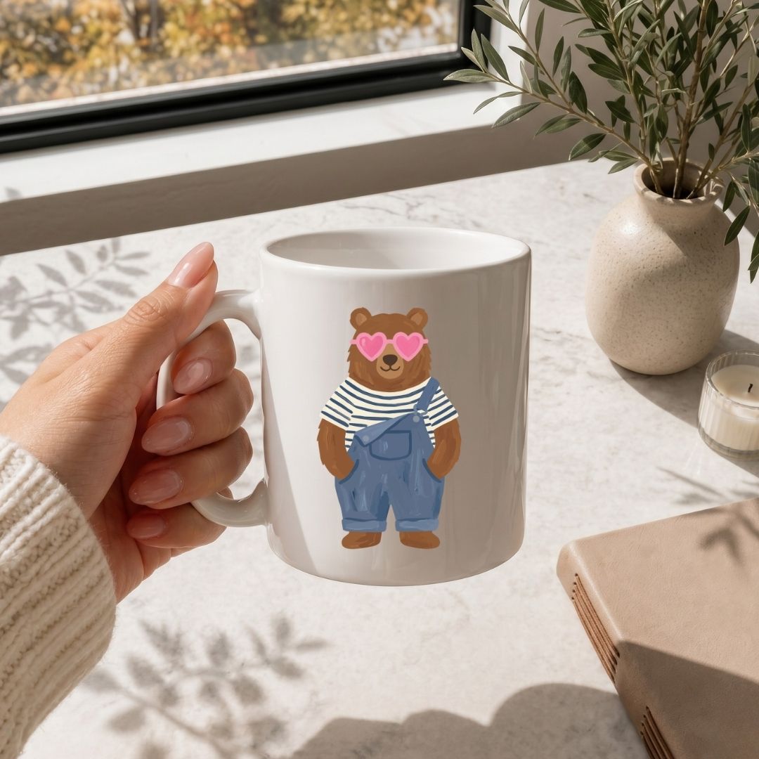 Person holding a mug with a bear design by a window with natural light.