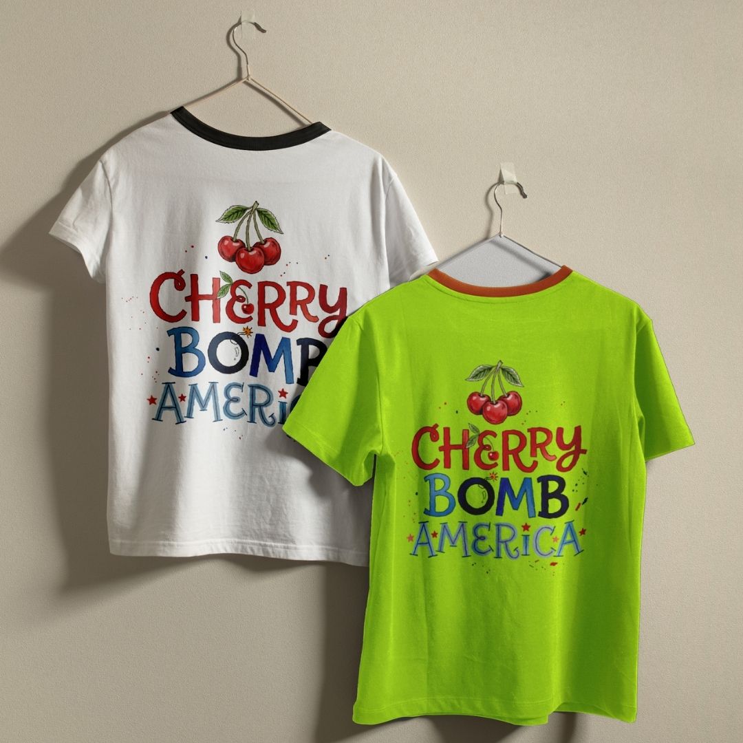 Two t-shirts with 'Cherry Bomb America' design on a beige background